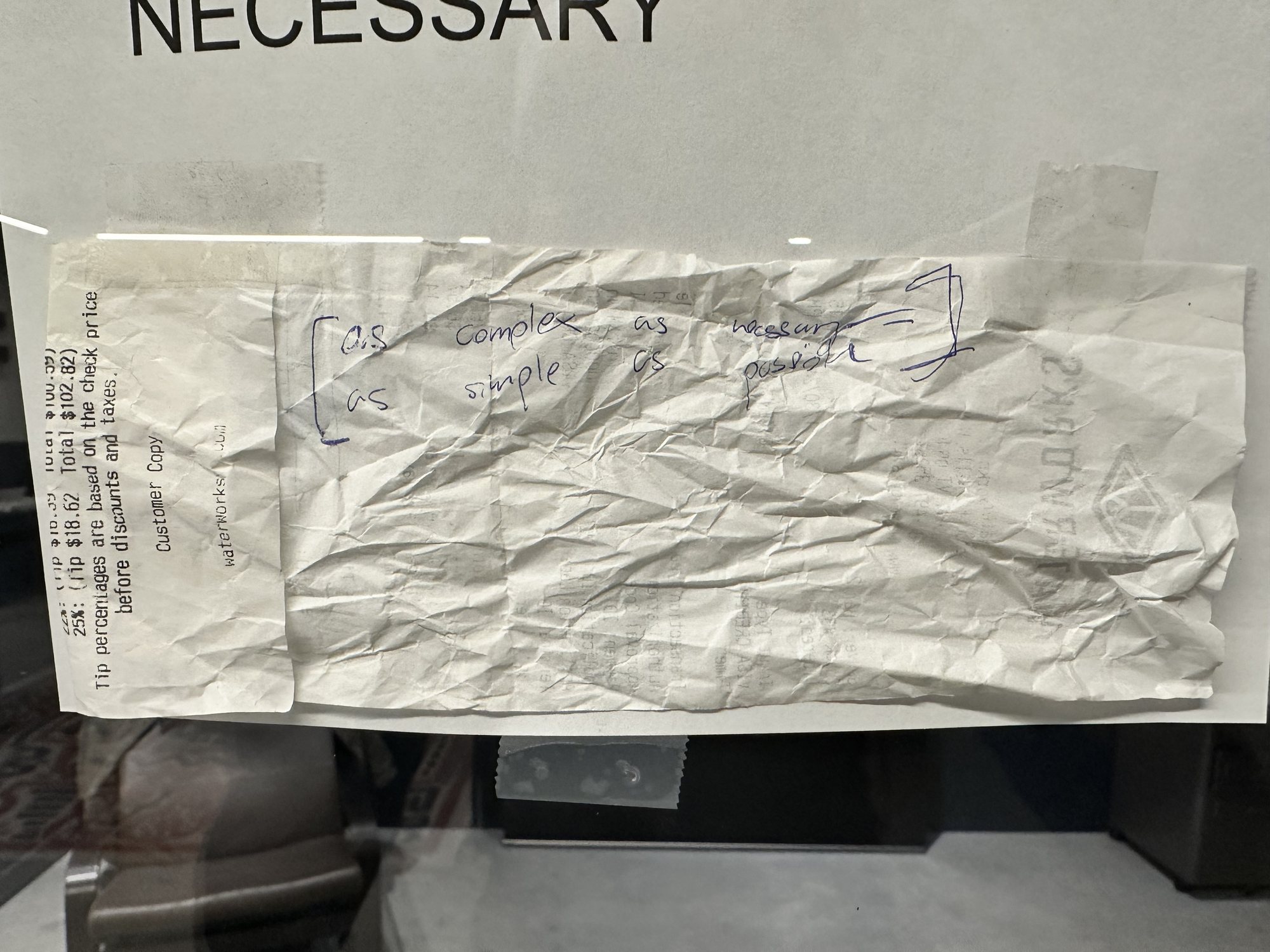 A crumpled receipt taped under a printed sign, with the line handwritten across it in pen.